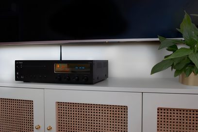 Taga Harmony HTR-1500CD zwart "all-in-one" high-fidelity systeem, vooraanzicht, oranje display, groene plant rechts