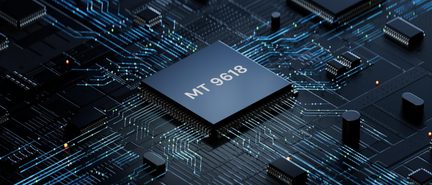 Slightly top-down perspective view of a close-up of a black printed circuit board with a square black microprocessor labeled “MT 9618”, plastic package with metal side pins, surrounded by fine blue-green luminescent traces