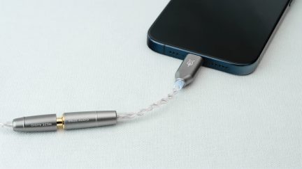 Hopeaäänikaapeli kytketty tummansiniseen älypuhelimeen valkoisella pinnalla