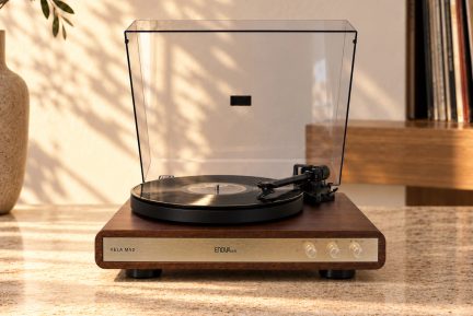 Brun Enova HiFi Vela MV2-pladespiller med guldfarvet front og åbent gennemsigtigt låg, med sort vinylplade