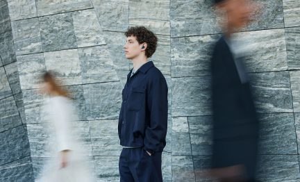 Zwarte draadloze in-ear oordop van glad plastic, compact en afgerond formaat, gedragen in het linkeroor van een persoon gezien van opzij