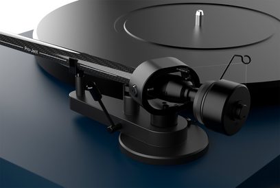 Hi-fi vinylspiller Triangle Lunar 3, nærbilde av den svarte tonearmen, sirkulært platetallerken, diagonal vinkel
