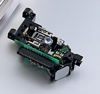 Indvendigt sort og grønt mekanisk system i en cd-afspiller, set oppefra i nærbillede, med synlige elektroniske og optiske komponenter