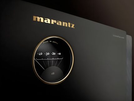 Fachada de amplificador negro mate en metal, vista oblicua, logo dorado de Marantz y gran medidor VU redondo con borde dorado graduado en dB