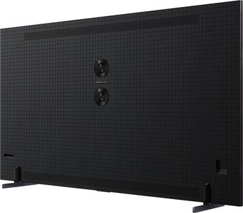 TCL 115C7K Ultra-HD-Fernseher in mattem Schwarz mit texturierter, gerasterter Kunststoffoberfläche, zwei zentral angeordneten runden Lautsprechern, schlanken Metallfüßen, Rückansicht leicht seitlich aufgenommen