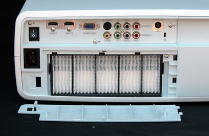 Forsiden af Sanyo PLV-Z2000 videoprojektor, med synlige tilslutninger og ventilationsgitter, placeret på en hvid holder