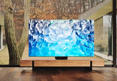 Televizor Samsung QE65QN900B 2022 zobrazující abstraktní modrý obraz, umístěný na dřevěném nábytku v moderním interiéru