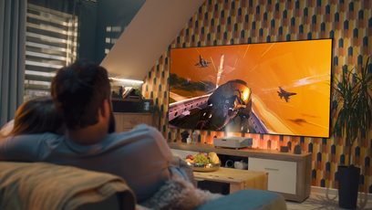Modern bir oturma odasında duvar ekranına hava muharebesi sahnesi yansıtan Optoma GT3500HDR videoprojektör