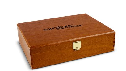 Caixa retangular de madeira fechada com a inscrição "soundcare superspikes" e fecho metálico dourado na frente