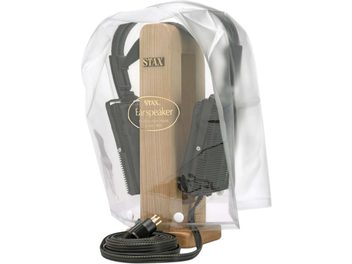 STAX CPC-1 skyddshölje i mjuk transparent plast, sedd framifrån, klockformad med två vita tryckknappar vid basen och en gyllene logotyp i mitten som visar det ljusa trästället för hörlurar och de svarta hörlurarna inuti