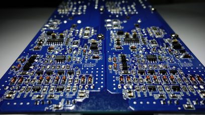 Blå printplader med talrige små sølvfarvede elektroniske komponenter arrangeret i et tæt og symmetrisk mønster