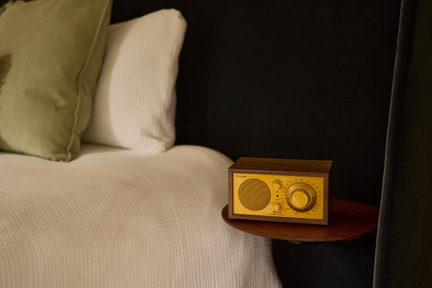 Radio in legno da tavolo, frontale giallo con altoparlante rotondo, quadrante graduato e pulsanti grandi, vista a tre quarti