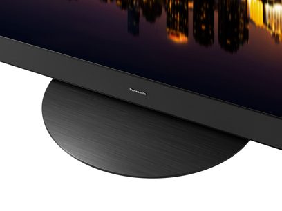 Téléviseur Panasonic TX-65MZ1500E, vue rapprochée du bord inférieur, cadre noir mat, logo argenté au centre