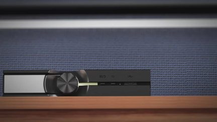 Svart hi-fi-lydforsterker med stor volumknapp, minimalistisk front, plassert på trehylle