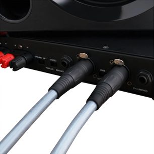 Primo piano vista posteriore di due cavi audio analogici Oehlbach Series 2 XLR 2 m grigio argento con guaina intrecciata, connettori XLR neri bloccati in un pannello audio nero