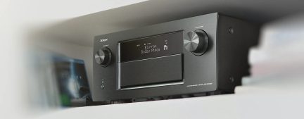Ricevitore audio/video nero visto frontalmente con schermo LCD che mostra "Blu-ray Dolby Atmos", pulsanti e manopole di controllo