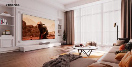 Moderne stue med stor vægmonteret skærm, beige sofa, rundt sofabord, hvide gardiner, trægulv, hvide hylder