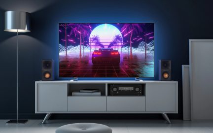 TV og hjemmebiografsystem i en stue, skærmen viser en retro-futuristisk bil i et synthwave-landskab