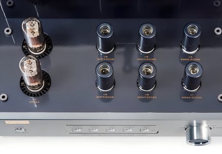 Fågelperspektiv på en hi-fi-rörförstärkare med mörkgrått metallchassi, två stora glaskolvar, sex rör under svarta cylindriska kåpor och frontpanel i borstad aluminium utrustad med väljare och ett stort silverfärgat volymreglage