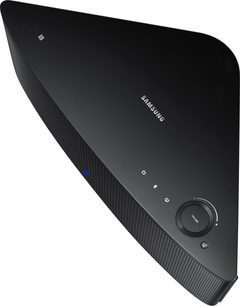 Trådløs, tilsluttet Samsung WAM 750 sort højttaler, set fra en trekvart bagside vinkel, med afrundet trekantet form og sort gitterbeklædning