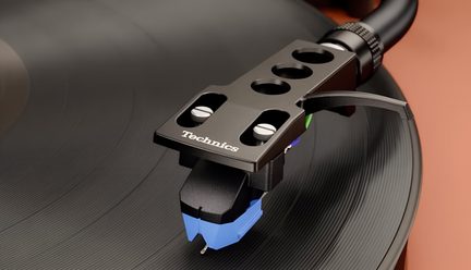 Sort metalpladespillerhoved med åbent skruefast cellestativ og blå nål, tæt påskudt skråt over vinylplade