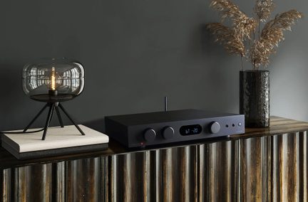 Amplificatore stereo audiolab nero su mobile in legno, display LED blu, con lampada in vetro fumé e vaso decorativo