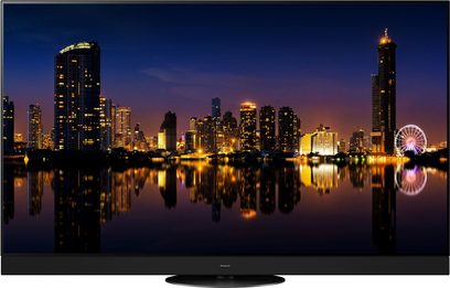 Téléviseur Panasonic TX-65MZ1500E affichant une vue nocturne de gratte-ciels illuminés et leur reflet dans l'eau