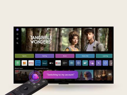 Fekete, fényes műanyagból készült lapos képernyős televízió, előlről látható, színes streaming felülettel, fekete műanyag távirányítóval az első síkban