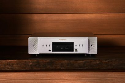 Плеєр CD Marantz CD60 сріблястого кольору, вид спереду, розташований на дерев'яній поверхні, цифровий дисплей синього кольору з показанням "020 01:15"