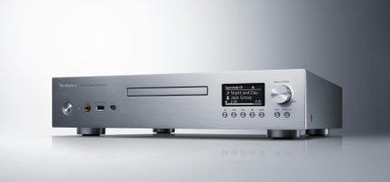 Lector de CD/SACD de red en aluminio cepillado plateado, vista de tres cuartos frontal, ranura para CD, pantalla, rueda de control, tomas para auriculares y USB