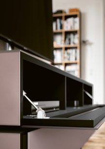 Sort TV-møbel med hylder i lyst træ, glaslåge, åben niche, på trappe i moderne indendørs miljø