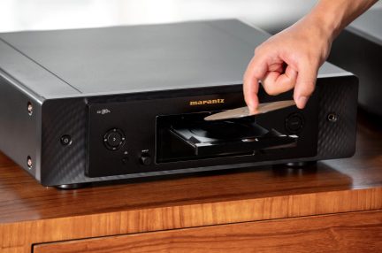 Schwarzer Marantz CD 50n CD-Player mit geöffneter Schublade und von Hand eingelegter Disc, Dreiviertelansicht von vorn