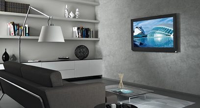 Vægmonteret fladskærms-TV i en moderne stue med hylder, designerlampe, gråt sofa og billede af moderne arkitektur på væggen