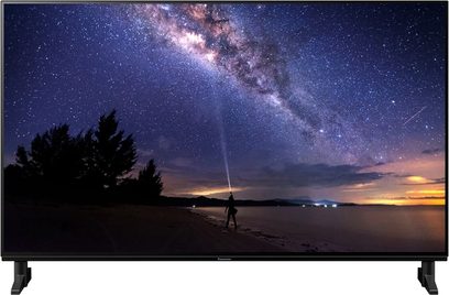Panasonic TX-48JZ1000E-fladskærm, der viser en nattehimmel med stjerner og Mælkevejen samt en menneskelig silhuet på en strand i tusmørke