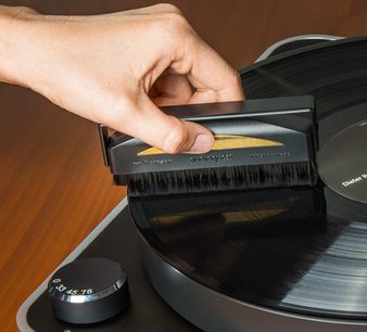 Mantendo uma escova antiestática Audioquest de fibra de carbono em um toca-discos de vinil, vista aproximada de cima