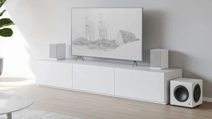 Hvitt hjemmekinoanlegg med to høyttalere på hver side av TV-en og en subwoofer på gulvet