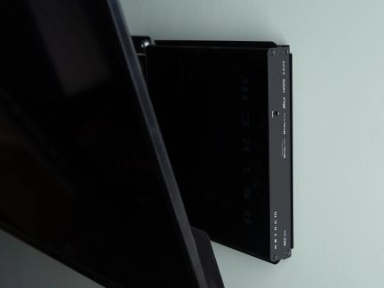 Бічний вигляд чорного телевізора, закріпленого на стіні, чорний корпус з білим текстом, гладка поверхня, видимі гвинти