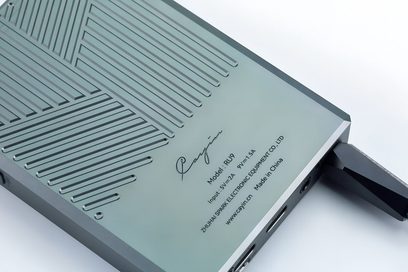 Bagside i let fugleperspektiv af den bærbare lydkonverter Cayin RU9 i anodiseret grågrøn aluminium, prydet med diagonale fræste riller og trykte mærkninger.