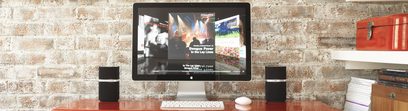 Computerskærm der viser en musikvideo på et træskrivebord med sorte Bowers & Wilkins MM-1 multimediehøjttalere