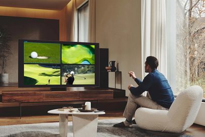 Samsung QE75QN800B 2022 fladskærms-TV, der viser en golfbane med en mand siddende i en hvid lænestol i en stue
