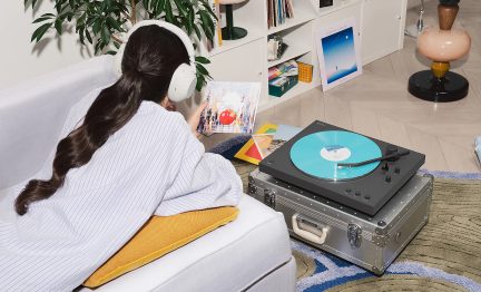 Sort Sony pladespiller med turkis vinylplade på aluminiums-kuffert, designerstue og kvinde med hvide hovedtelefoner