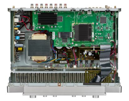 Gümüş renkli metal şasi içindeki bir amplifikatörün içi, yeşil PCB, transformatör, siyah soğutucular, kablo demetleri, üstten görünüm