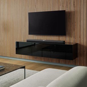 Black Bowers & Wilkins Panorama 3 soundbar on light wood cabinet, in front of vertical wood slat wall