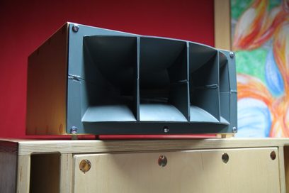 Altec Lansing Onken 360 rød højttaler, set forfra, 3 sorte rum, 4 sølvfarvede knapper, på lyst trækabinet