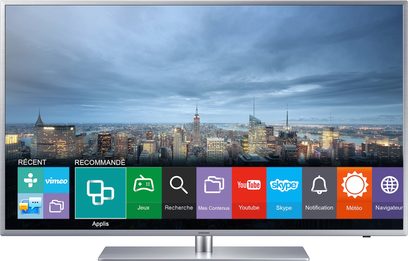 Samsung UE55JU6410 TV viser apps på en baggrund af et bymiljø i skumringen med oplyste skyskrabere