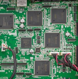 Grønt printplade med mange rektangulære og firkantede sorte elektroniske chips fra Denon AVR-X4300H-forstærkeren, tæt på visning