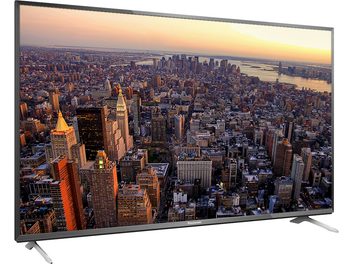 Panasonic TX-50CX700E TV displaying an aerial view of a dense city with numerous skyscrapers at sunset