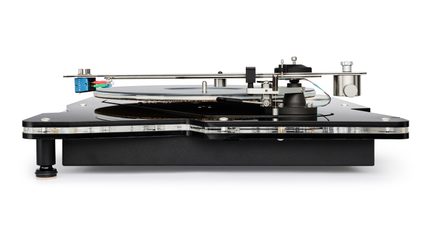 Sort pladespiller med cirkulær, gennemsigtig akrylpladetallerken, transparent bund, metal-tonearm med blå pickup og cylindrisk counterweight, set forfra