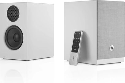 Et par hvite Audio Pro A28 W-høyttalere, den ene med synlige svarte høyttalerelementer, den andre med grå frontgrill, med fjernkontroll