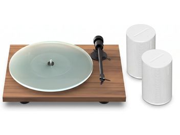 Vinylskivspelare med träsockel, glasskivtallrik och svart tonarm, med två vita Sonos-högtalare